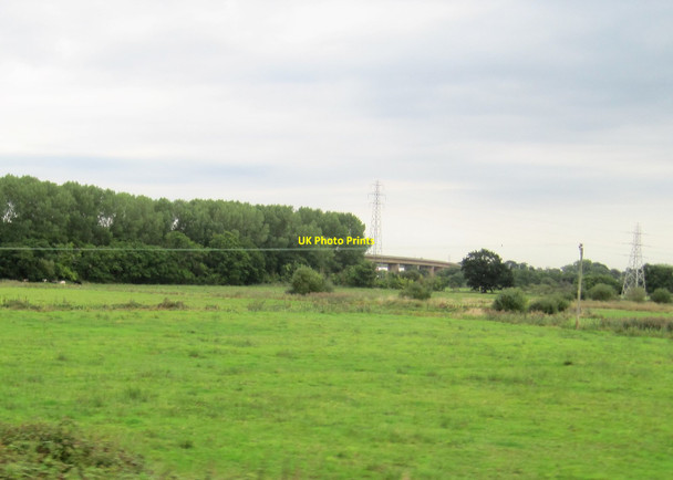Photo 6"x4" View from a Plymouth-Exeter train - fields and pylons near the M5 Exminster c2016