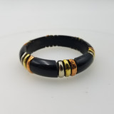 Key details:

Base: Smooth, glossy black band (looks like resin, lacquered metal, or polished horn/acrylic).

Design: The bangle is made of segmented black sections, separated by sets of metal spacer rings.

Metal accents: The spacers alternate in three tones:

Silver-tone

Gold-tone

Copper/rose-gold tone

Style vibe: Contemporary / minimalist statement, with a black + tri-tone metal look that pairs easily with other jewelry.