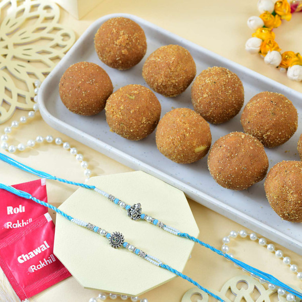 Ganesh And Suriya Set Of Two Rakhi With Besan Laddu