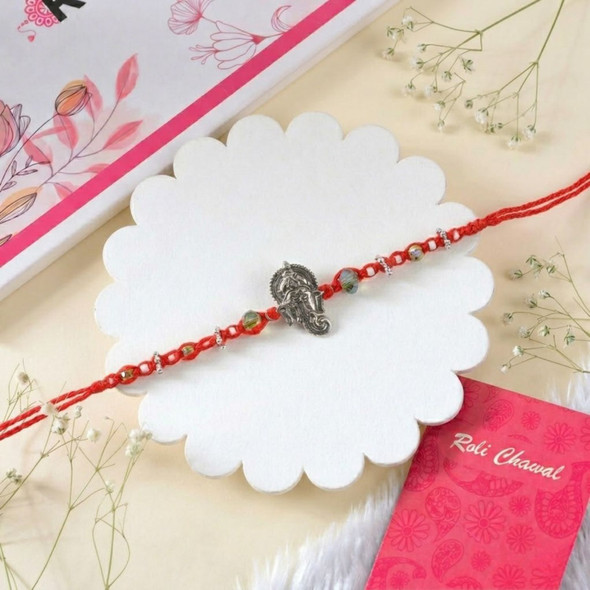 Lord Ganesha Rakhi with Red Thread and Beaded Accents