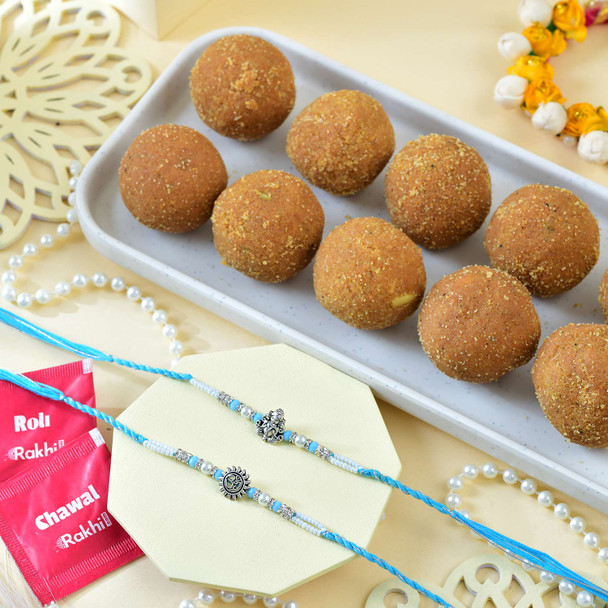 Ganesh And Suriya Set Of Two Rakhi With Besan Laddu