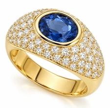 Bezel set 1.5 carat oval lab grown pave domed diamond simulant cubic zirconia and man made sapphire gemstone ring in 14k yellow gold.