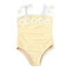 A butter-yellow Shade Critters Butter Daisy one-piece swimsuit is shown at an angle, featuring a row of white and yellow 3D crochet daisies across the chest and white straps with floral appliqués.