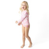 Side view of Pink Paradise girls long sleeve one piece swimsuit on model.