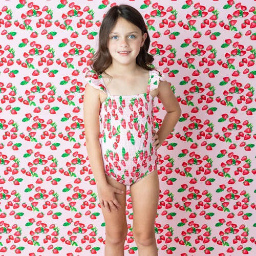 Shade Critters girls smocked one piece swimsuit in strawberry bliss print with crochet trim, cute fruit print kids swimwear shown on model.