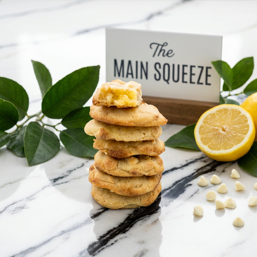 Stack of freshly baked artisan lemon white chocolate cookies garnished with fresh lemons and white chocolate chips.