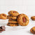 Drive Me Nuts gourmet cookies with pecans and chocolate chips stacked on a white surface