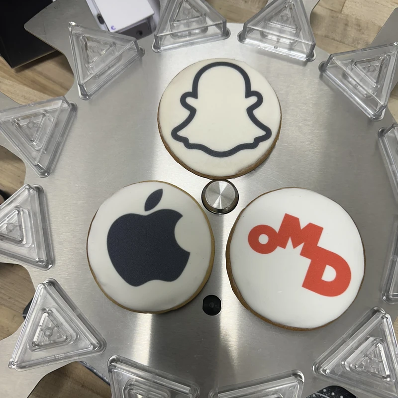 Snapchat, Apple, and OMD logo cookies on the edible printer tray.