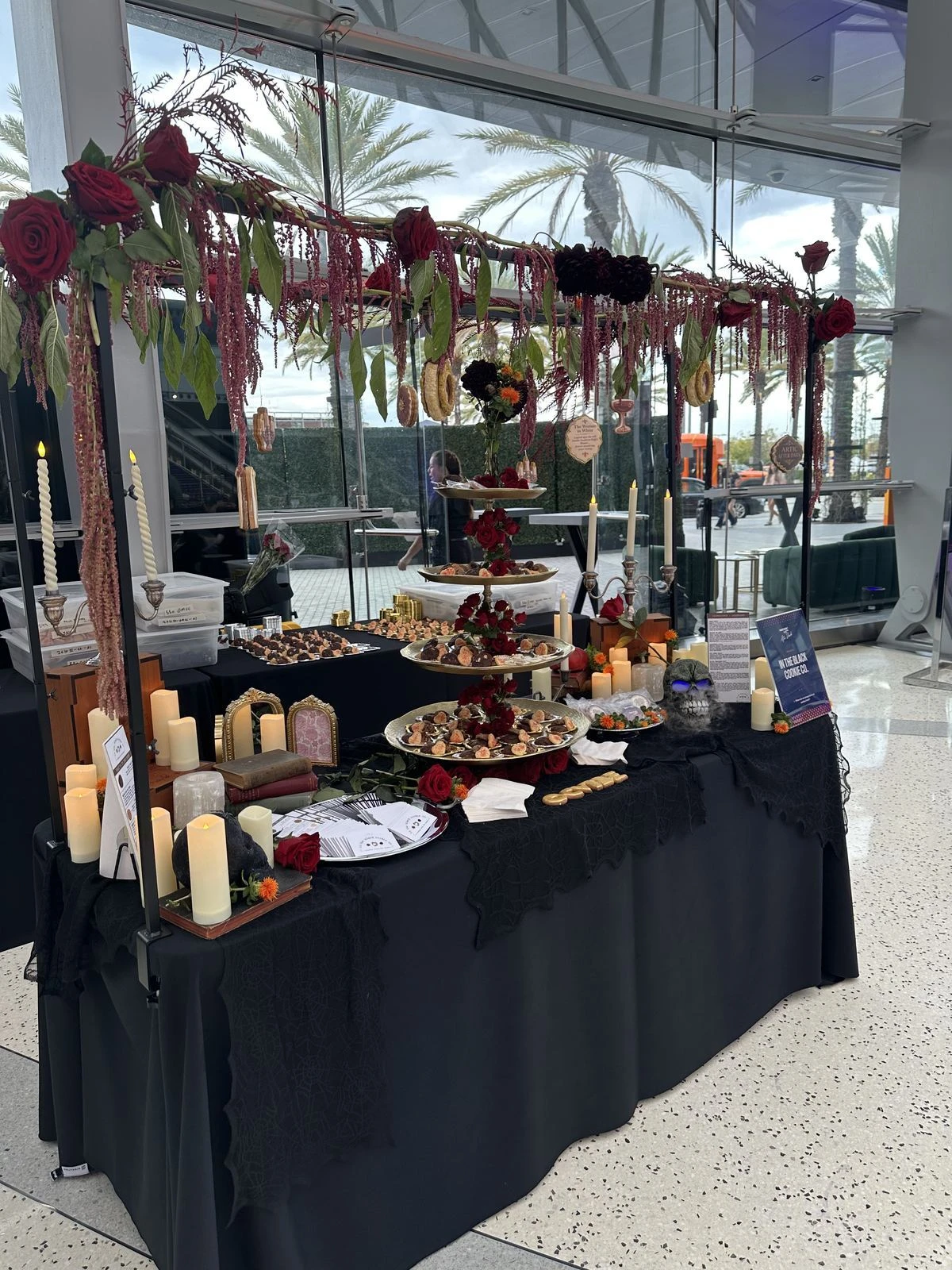 In the Black Cookie Co's event table at ARTIC with black linens, red roses, candles and tiered trays of cookies