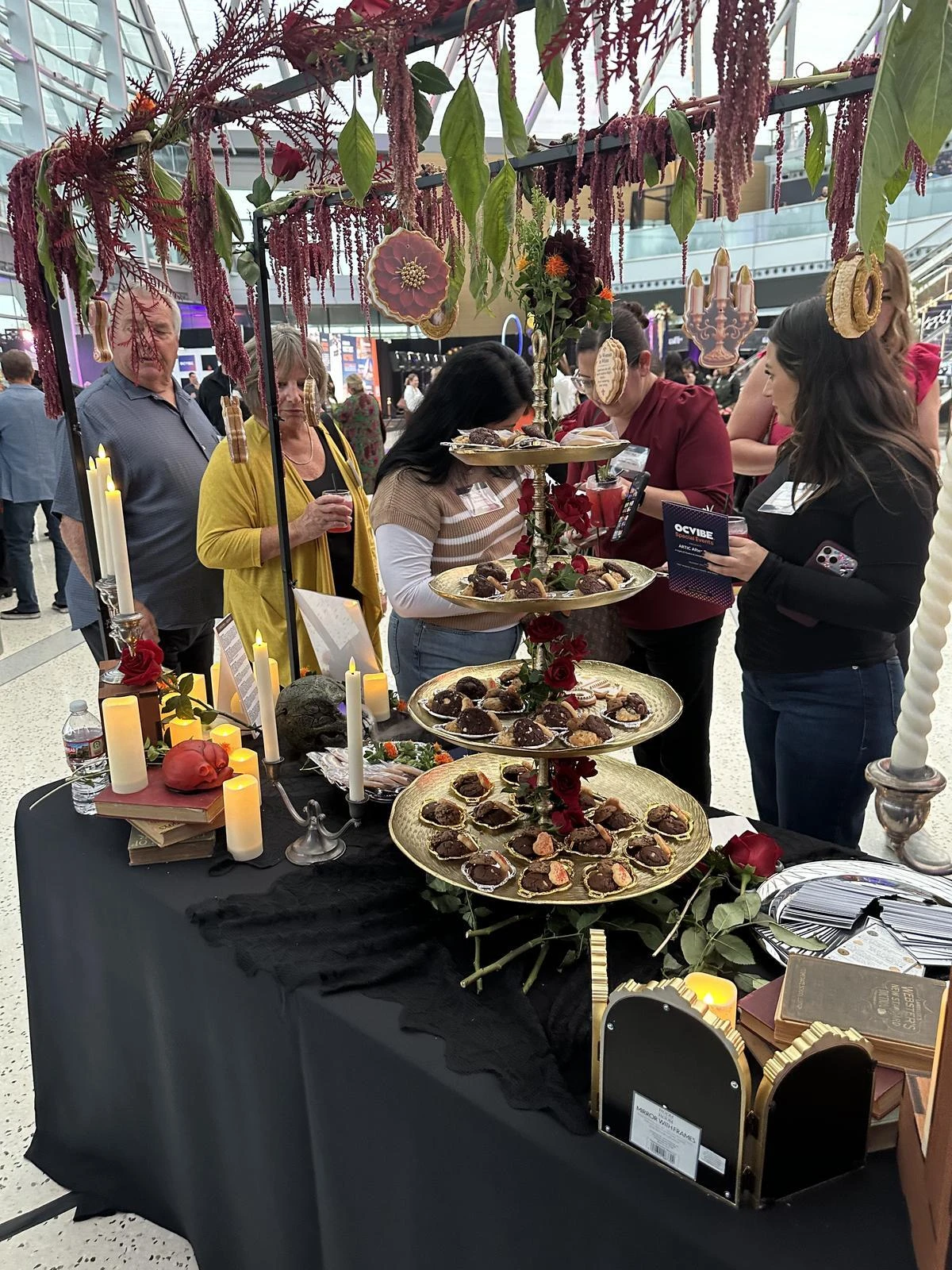 Guests gather around tiered gold trays of cookies at the In the Black Cookie Co table at Arctic After Dark