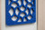 Close-up of a blue felt acoustic panel with a repeating cutout pattern mounted on a wall.
