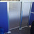 Close-up of blue fabric office cubicle panels with frosted sliding door sections and aluminum frames.