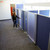 Person opening a frosted sliding door on blue fabric office cubicles in a modern workspace.
