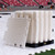 White interlocking flooring panels stacked on a pallet inside a stadium.