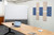 Modern meeting room with a wooden table, open laptop, rolling whiteboard, and decorative acoustic wall panels.