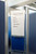 Rolling whiteboard with handwritten project status between blue office partition panels.