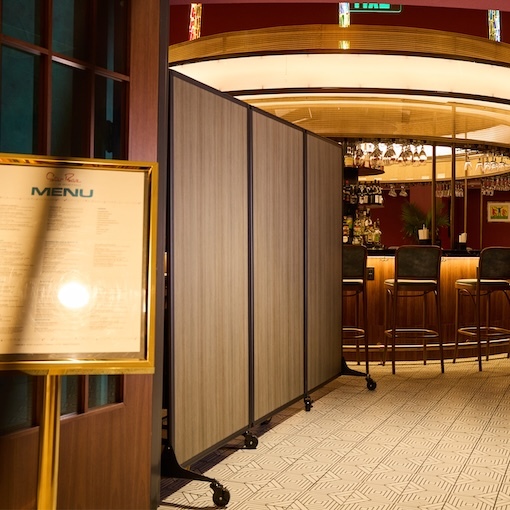 Restaurant interior with a menu stand and a movable partition screen in front of a bar.
