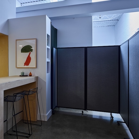 Folding privacy screen dividing a small seating area in a contemporary interior.