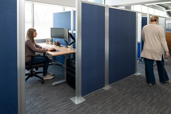 Blue Hush Panel office partitions creating private employee workstations in a modern open office.