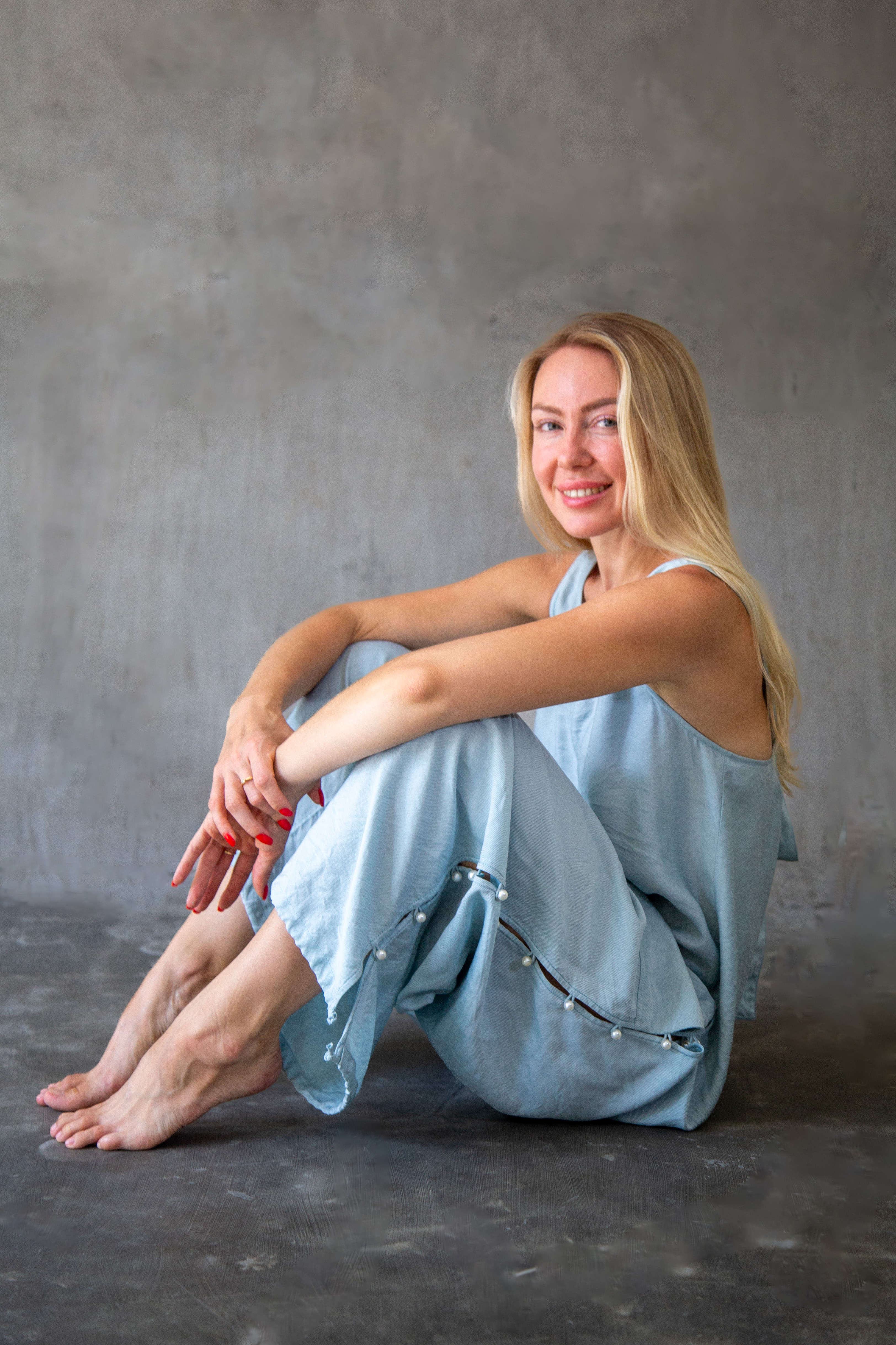 Model sitting cross-legged in a light blue wide-leg jumpsuit, Eluvare yoga-inspired luxury loungewear and meditation wear.