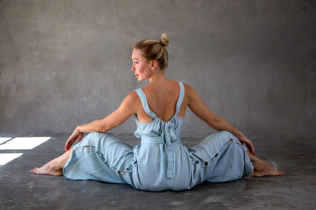 Back View of Model
Back view of a model in a blue sleeveless jumpsuit with open back and tie closure, Eluvare elegant transformation design.