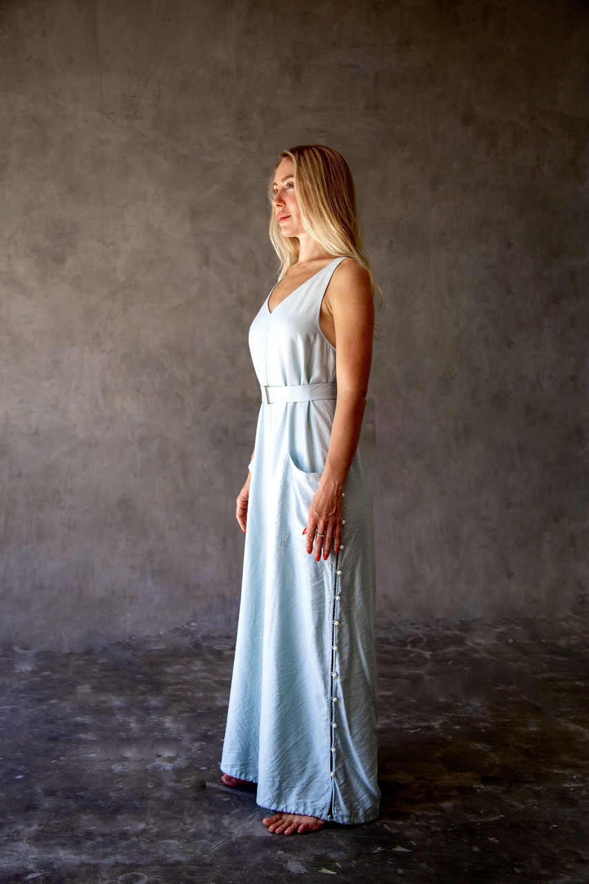 Full side profile of a model wearing an Eluvare blue transformation jumpsuit, showing convertible silhouette and wide-leg design.