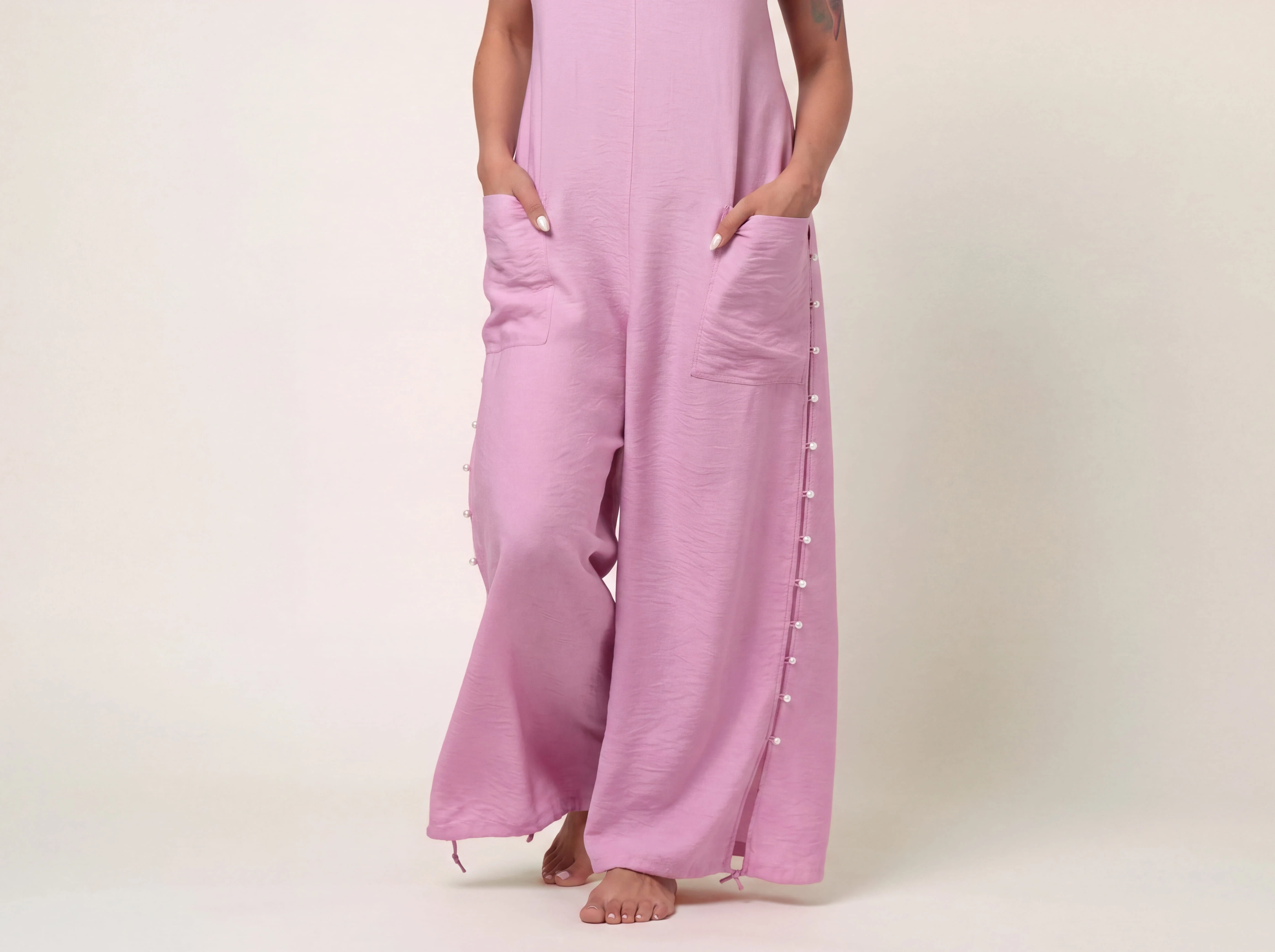 Close-up detail of the rose pink fabric and wide-leg cut of the ELUVARE jumpsuit