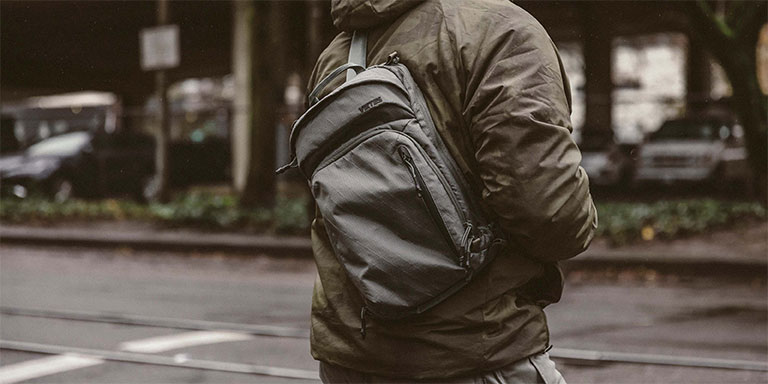 Person commutin in rainy weather wears jacket and small EDC sling bag.