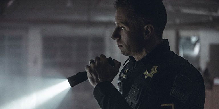 Police officer at night checks the area with handheld flashlight