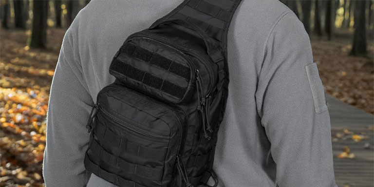 Man in gray fleece jacket wearing a black sling bag