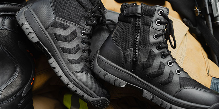 Side zip tactical boots laying on top of other duty clothing and equipment