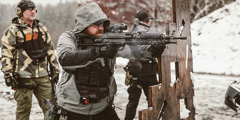 Men in weather-proof gear training at the range in snow