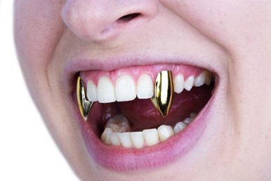 Scarecrow Glam Vampire Fangs in Gold (on model). Sold by Norcostco.