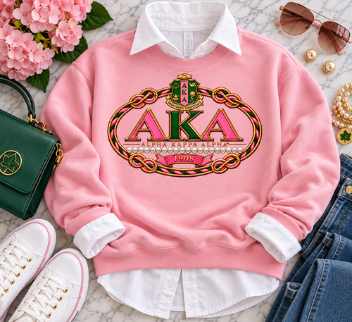 A timeless tribute to Alpha Kappa Alpha Sorority, Incorporated®, this premium design brings together signature pink and green with rich old-gold detailing for an elevated, sophisticated look. The bold AKA lettering is framed by an intricate braided rope motif, accented with pearls and the distinguished crest, while 1908 anchors the design in more than a century of sisterhood, scholarship, service, and legacy.

Designed for the woman who appreciates her AKA heritage with a polished, fashion-forward aesthetic, this statement piece transitions effortlessly from chapter events and conferences to Founders’ Day celebrations, homecoming, or an elevated everyday look. Pair it with a crisp white Oxford, denim, or your favorite accessories for unmistakable Pretty Girl style.

Design details: Signature AKA pink and green • Luxe old-gold accents • Pearl detailing • 1908 heritage detail • Premium statement artwork • Made to order

Apparel and accessories shown in styled images are for presentation purposes; actual garment style and color may vary by selection.