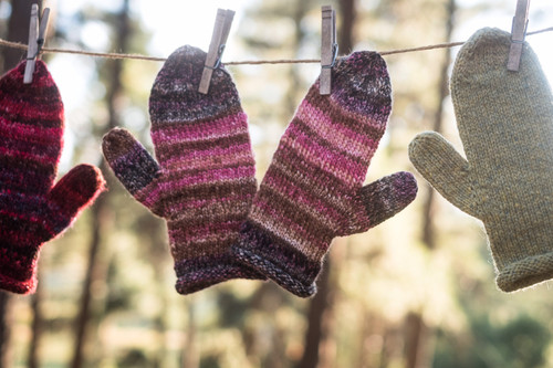 pink and black striped mittens hanging on a clothes line