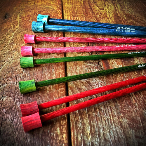 Knitter's Pride Dreamz 10” & 14” wooden knitting needles, displayed on a natural surface, showcasing assorted colors and brand's signature wooden design.