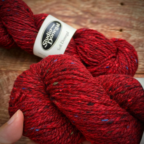 Studio Donegal Soft Donegal Tweed DK Merino Wool yarn skeins in deep red with subtle flecks, branded with Studio Donegal label, textured, woven yarn.
