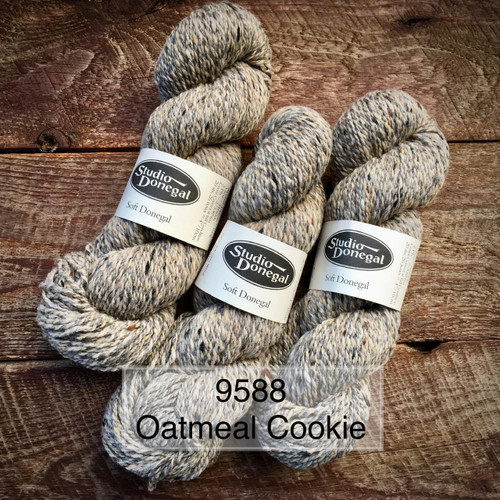 Studio Donegal Soft Marls marled merino wool yarn, oatmeal cookie color, in three skeins, on a wooden background, labeled 9588.
