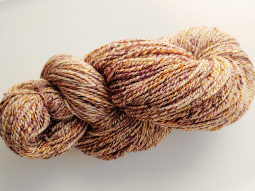 Luxury handspun merino wool skein in warm autumn tones, 2-ply sport/DK weight yarn with rich marled texture and subtle color variations.