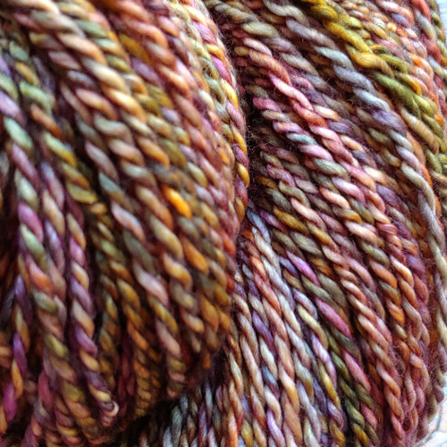 Luxury handmade merino wool yarn from Forever Winding Wool in November's autumn-inspired colors, featuring blended shades of pink, orange, yellow, and brown.