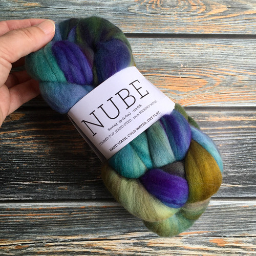 Malabrigo Nube Indiecita 100% Merino Wool Roving, 4oz weight, multicolor shades of blue, purple, green, and brown, Malabrigo brand fiber suitable for spinning and felting crafts.