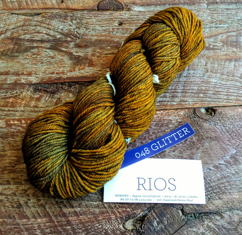 Malabrigo Rios Glitter yarn in Bronze Gold Worsted Merino, skein with label, showcasing bronze and gold multicolored sparkle yarn.