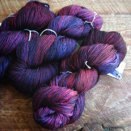 Malabrigo Ríos Yarn - Syrah Grapes, deep wine purple hand-dyed worsted merino, made by Malabrigo, in a rich color variation on a wooden surface. Malabrigo Ríos Yarn - Syrah Grapes, deep wine purple hand-dyed worsted merino, made by Malabrigo, in a rich color variation on a wooden surface.