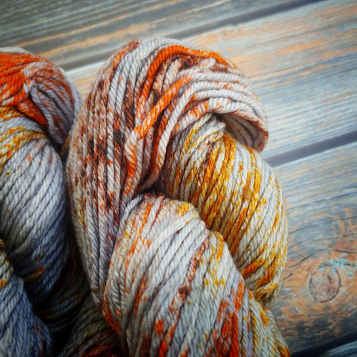 Malabrigo Rios Siri yarn, speckled gray and rust superwash merino wool, showcasing vibrant orange, yellow, and gray hues in a skein, from the brand Malabrigo, highlighting its unique colorway and texture. Malabrigo Rios Siri yarn, speckled gray and rust superwash merino wool, showcasing vibrant orange, yellow, and gray hues in a skein, from the brand Malabrigo, highlighting its unique colorway and texture.