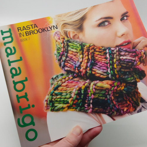 Malabrigo Pattern Book 7: Rasta In Brooklyn, colorful knitted scarf on blonde woman, vibrant hues, knitting patterns, Malabrigo branding on cover.