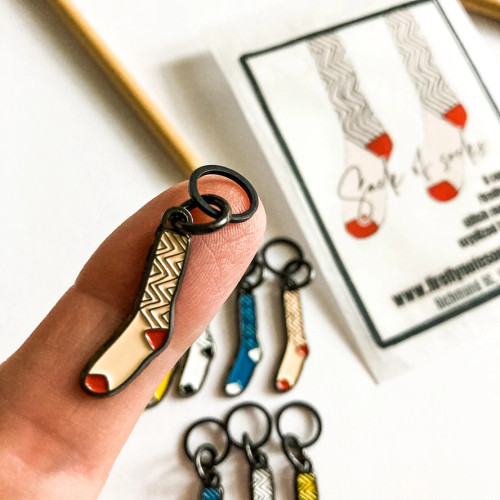 Handheld view of colorful enamel sock stitch markers showing the dainty 10mm ring size.
