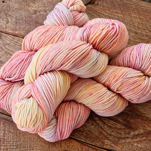Multiple hanks of Malabrigo Rios Rosalinda 398 showing hand-dyed rose, raspberry, and magenta tones