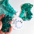 Mindful Collection Stitch Marker Mega Pack in teal, featuring assorted sizes and shapes of green stitch markers on a white background.
