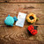 Lantern Moon retractable tape measure, knitting tool, alongside crochet blue fish, yellow flower, and red ladybug on rustic wooden background, sewing accessories.