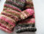 pink black, brown and gray  mittens laying on a white background